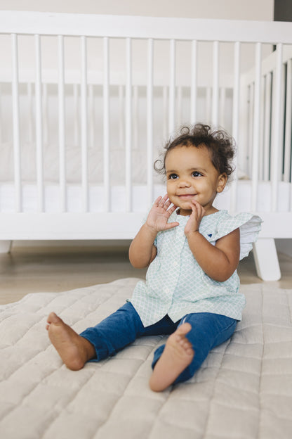 Smiling baby girl wearing stylish outfit from London Lark that includes green shell print and jeans. 9 12 month clothes.